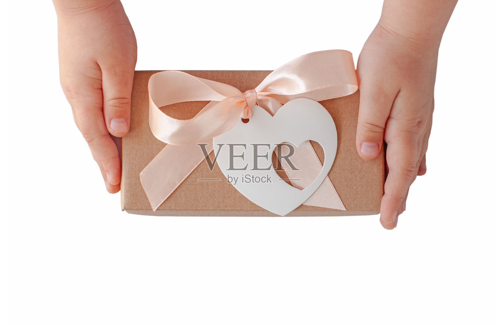 儿童手握礼品盒与丝带蝴蝶结和心卡标签。牛皮纸包装平铺。捐赠的概念照片摄影图片