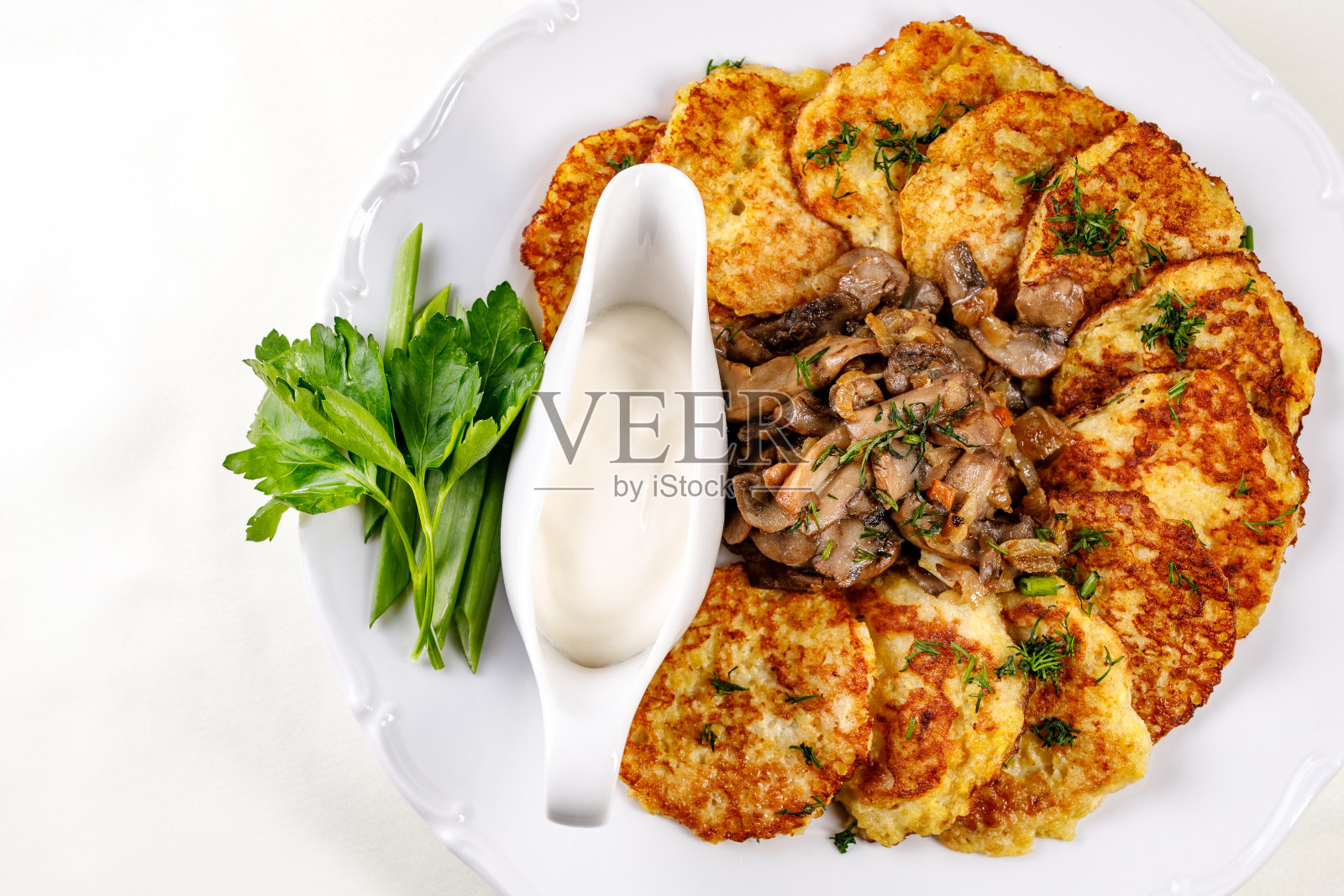 土豆煎饼配蘑菇和酸奶油放在一个白色的盘子里照片摄影图片