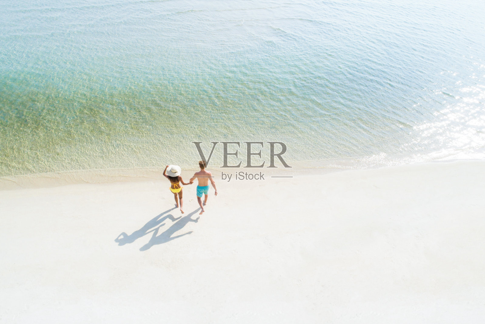 一对情侣在海滩上走进海水里照片摄影图片