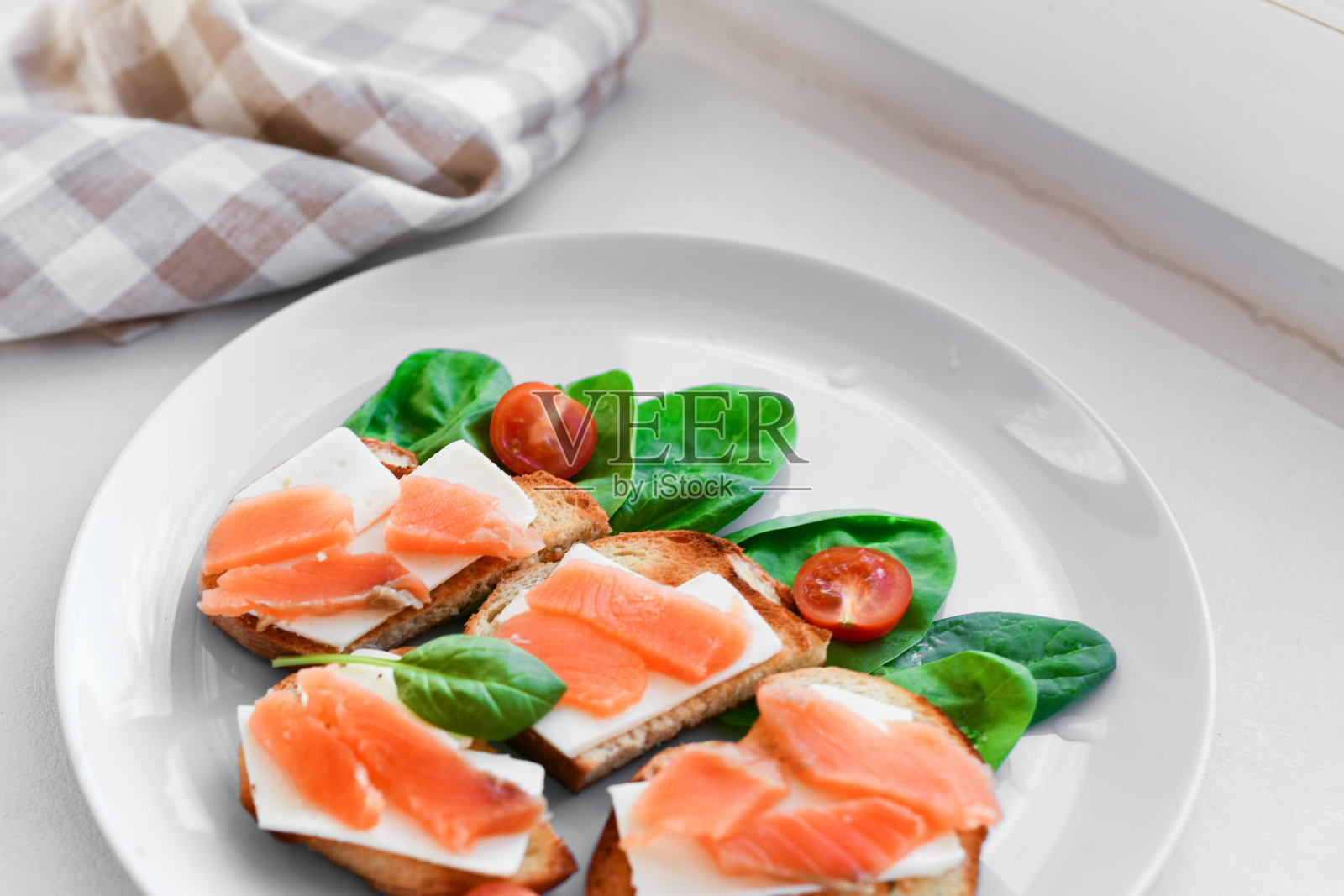 三明治和红色的鱼放在白色的盘子里。装饰着绿色照片摄影图片