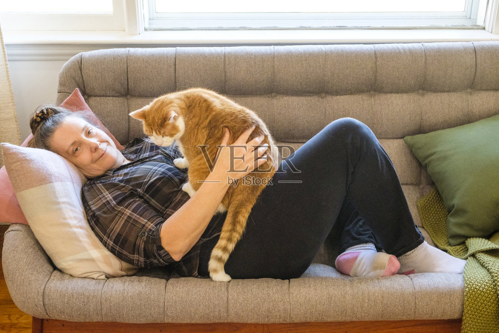 一位中年妇女在沙发上抚摸她的猫照片摄影图片