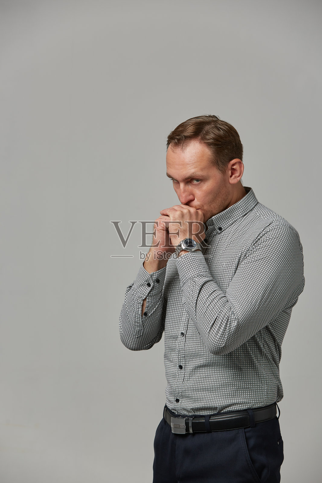 一个穿着灰色衬衫的年轻人看了看他手上的钟。情感、勇敢的面孔。孤立白底文案空间广告及商业设计照片摄影图片