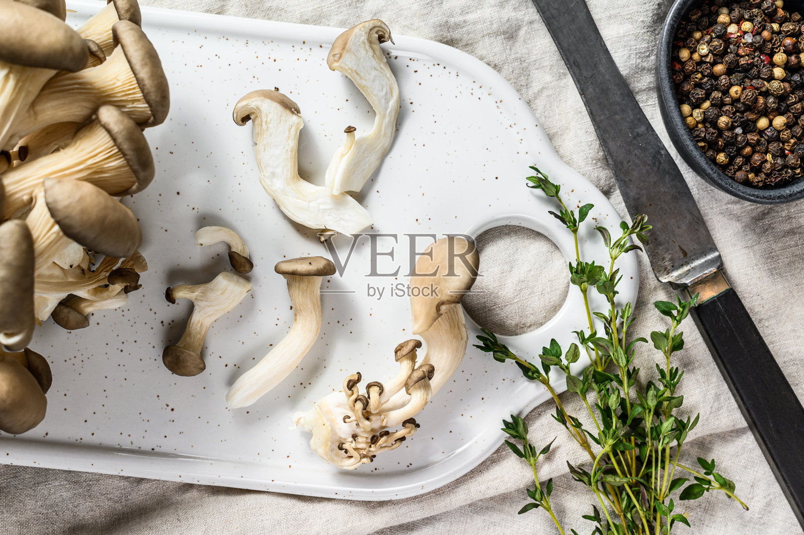 新鲜平菇和百里香放在白色切菜板上。灰色的背景。俯视图照片摄影图片