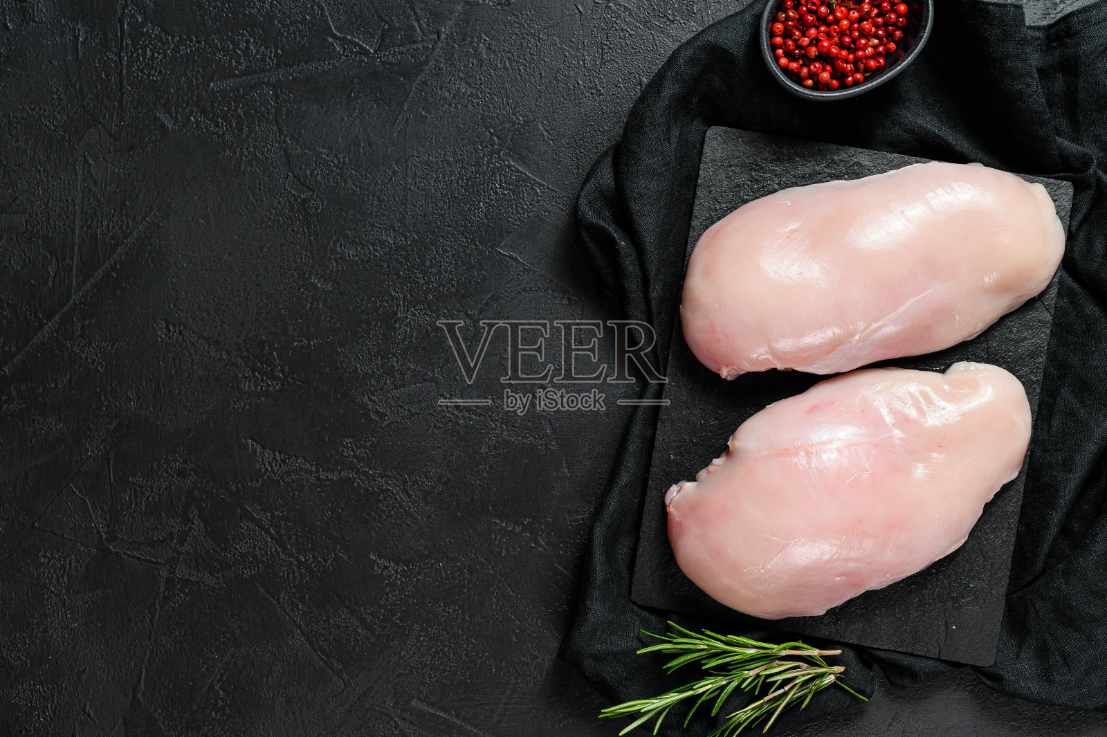 切菜板上的生鸡胸肉。新鲜的角。黑色背景。空间的文本照片摄影图片