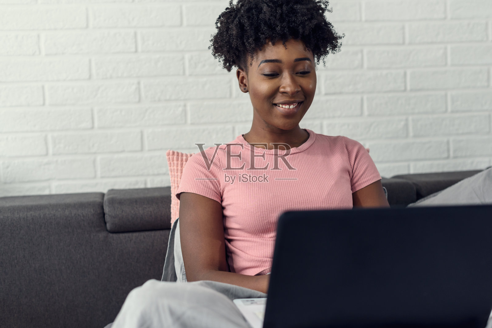 年轻的非洲裔美国妇女在床上使用笔记本电脑照片摄影图片