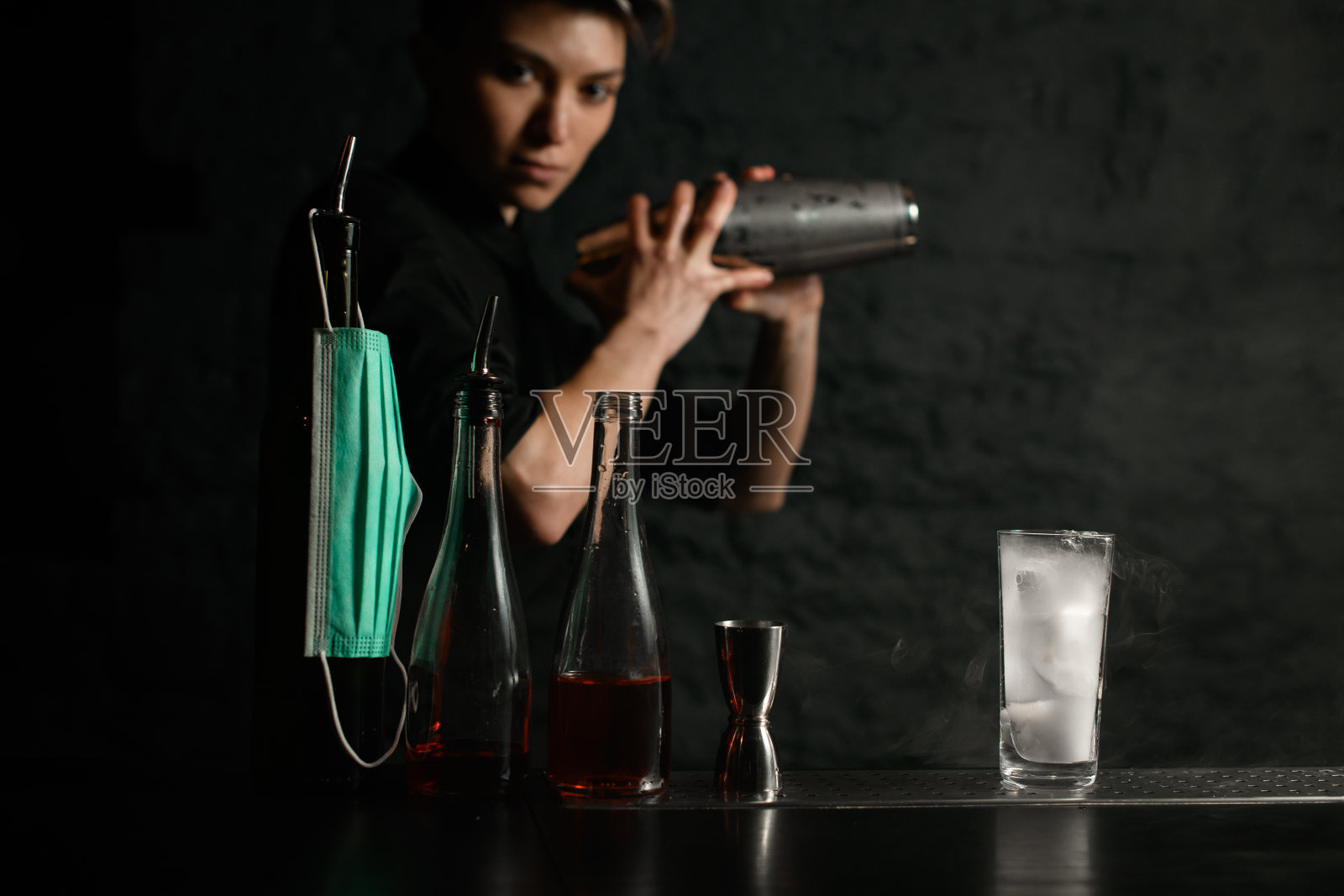 吧台上放着几个带医用口罩的瓶子。照片摄影图片