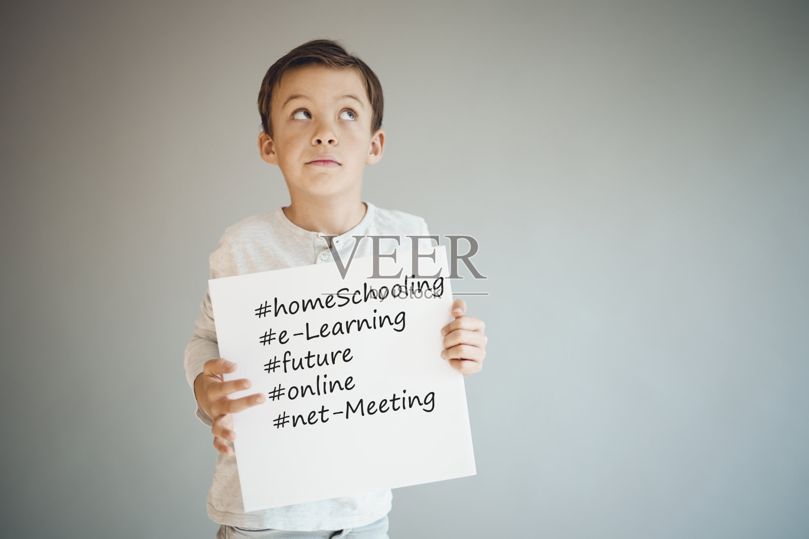 一个男孩举着白色的牌子上面写着家庭教育等等照片摄影图片