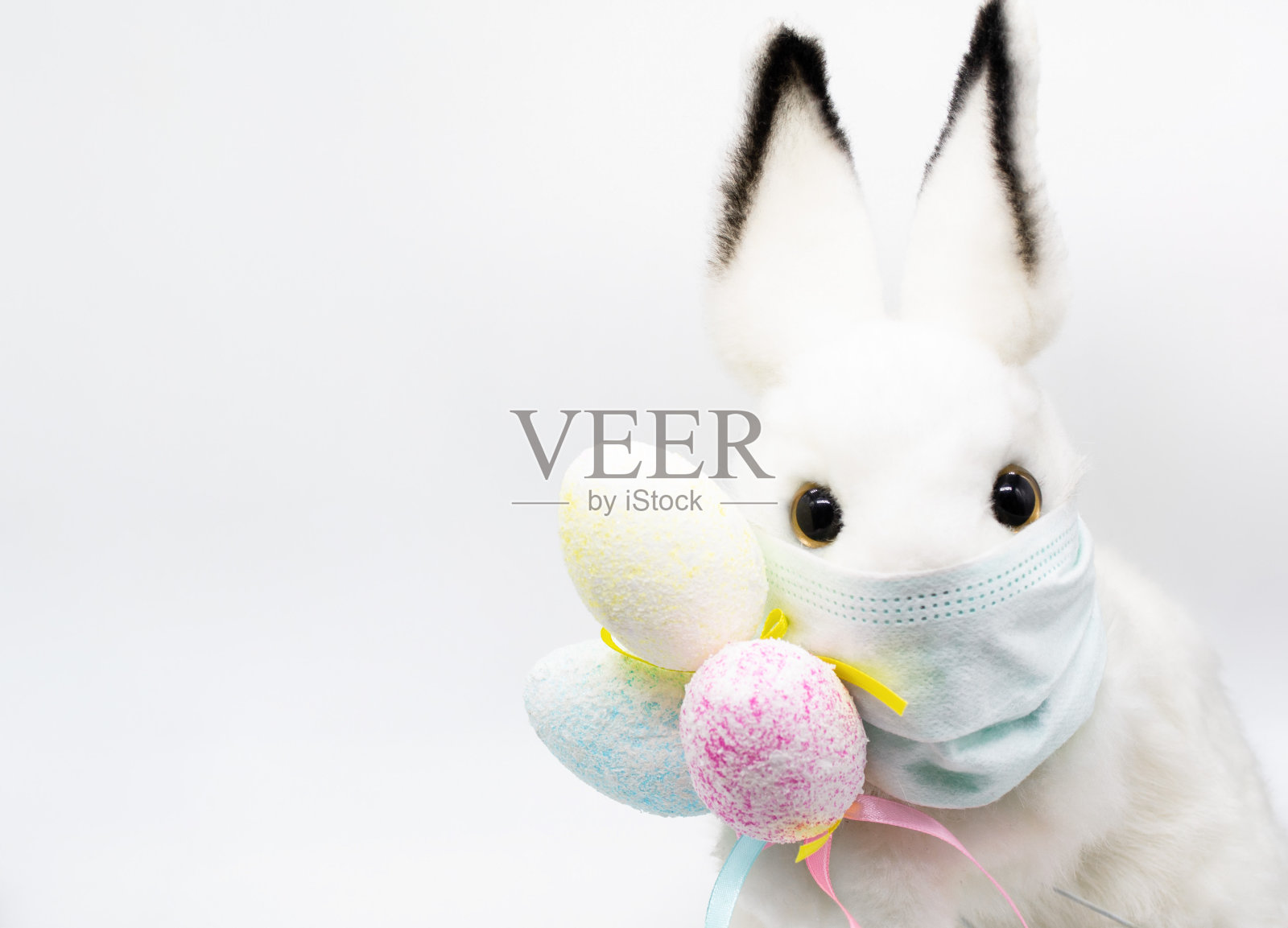 复活节兔子在一个面部医疗面具与一束彩色鸡蛋。复活节的概念和冠状病毒感染的隔离。就像一张祝福你的明信片照片摄影图片