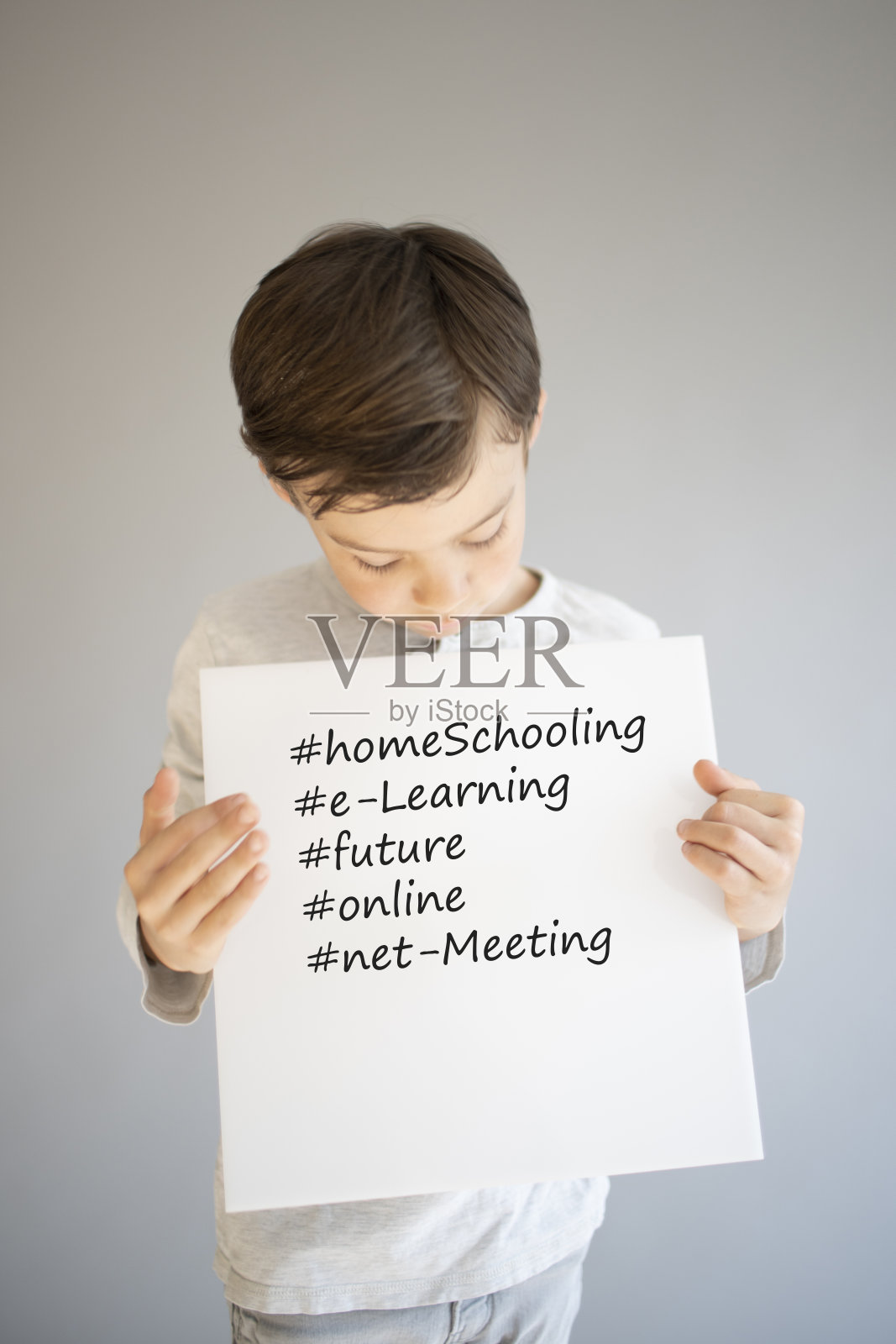 一个男孩举着白色的牌子上面写着家庭教育等等照片摄影图片