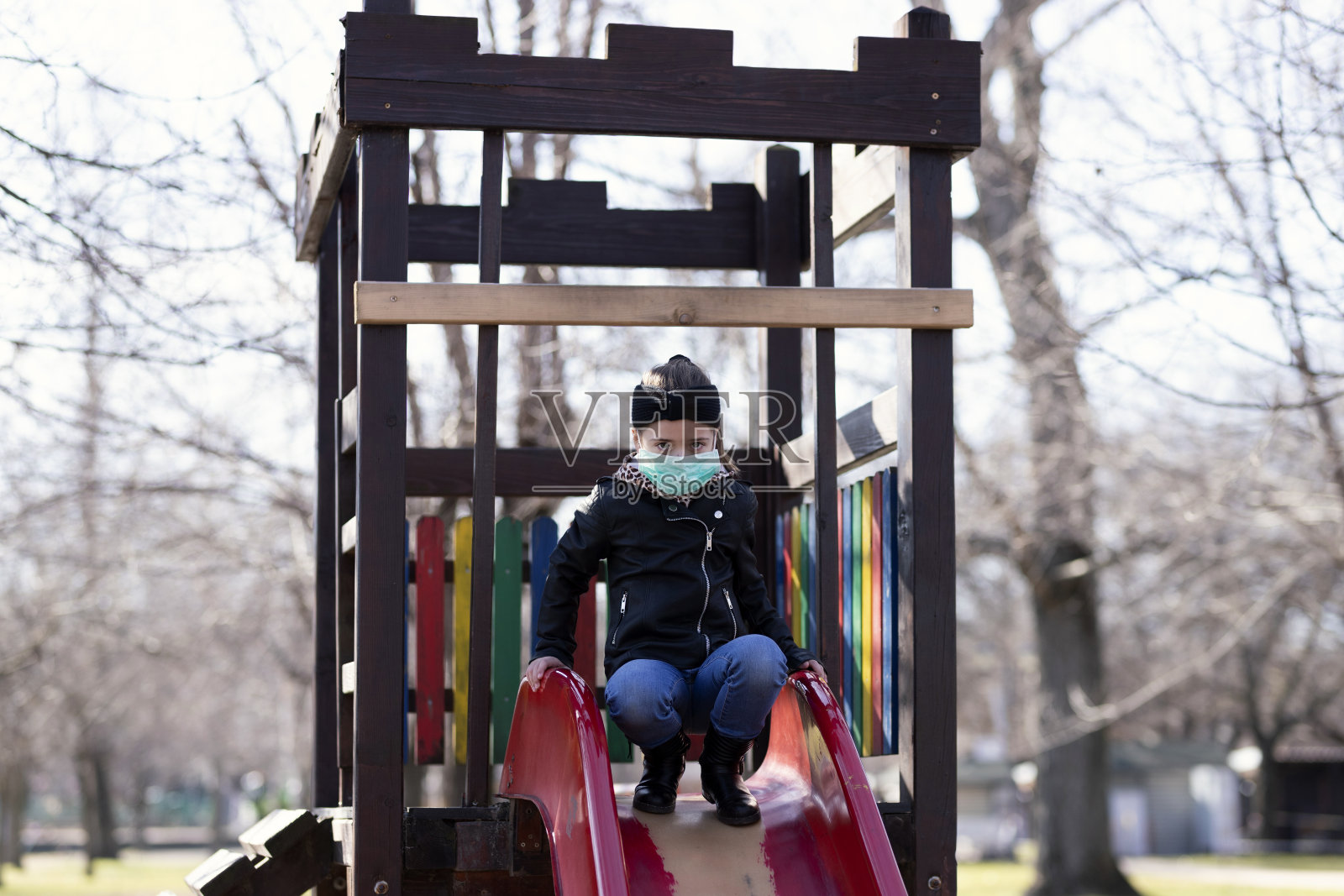 戴着外科口罩的女孩在操场上滑雪橇照片摄影图片