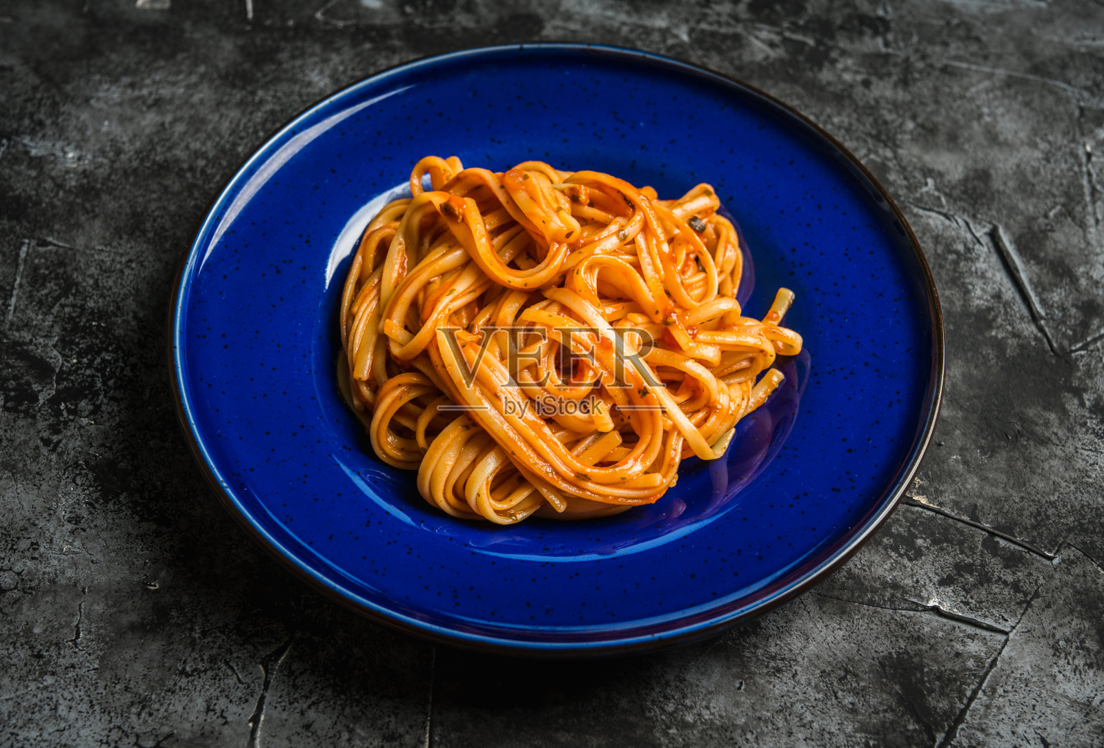 在乡村背景下，用蓝色盘子盛着番茄酱的传统意大利面照片摄影图片