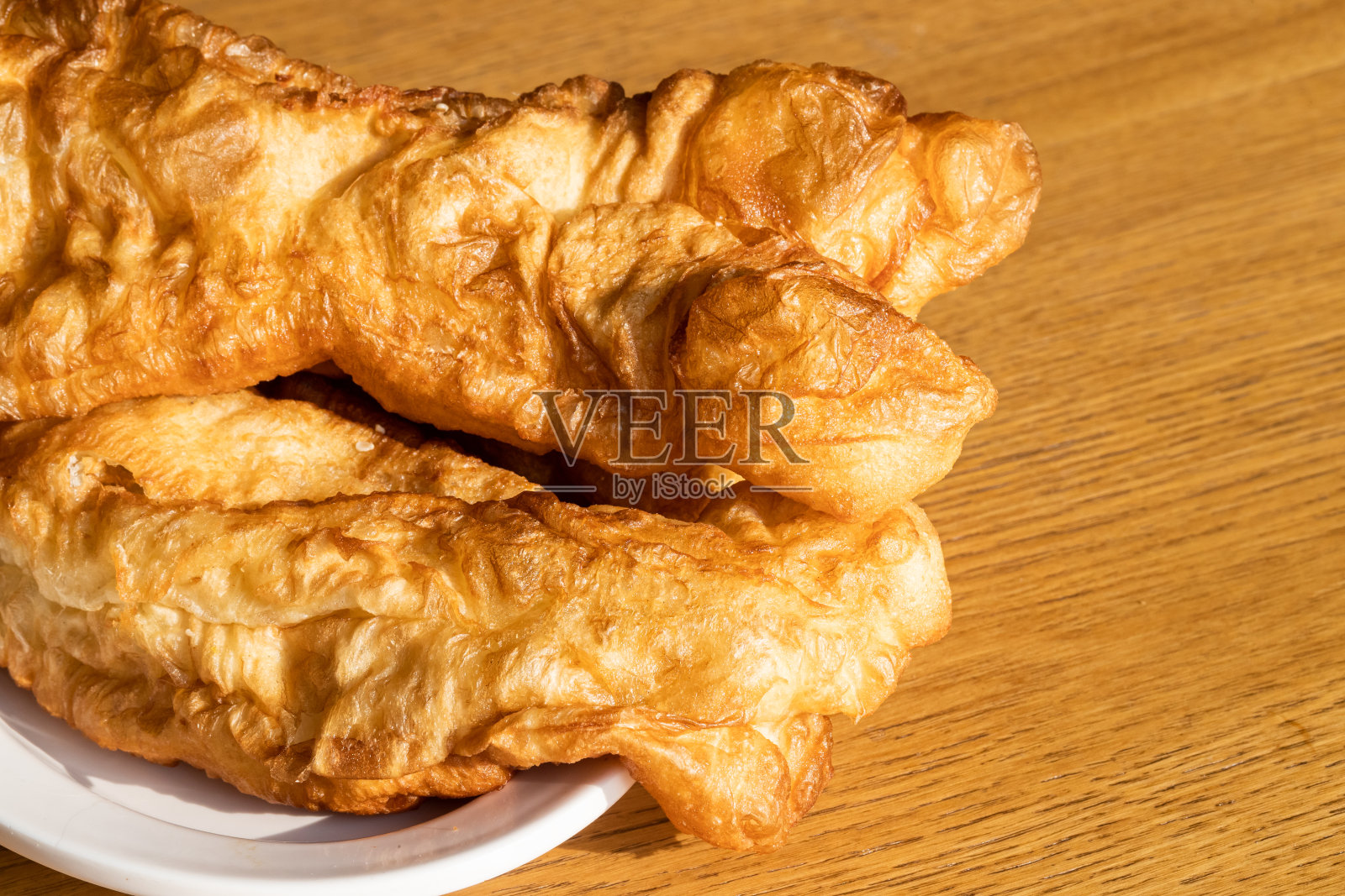 桌上的中国菜:油条(炒锅、瓜子、油条、甜甜圈、油条)、金色长油条、早餐照片摄影图片