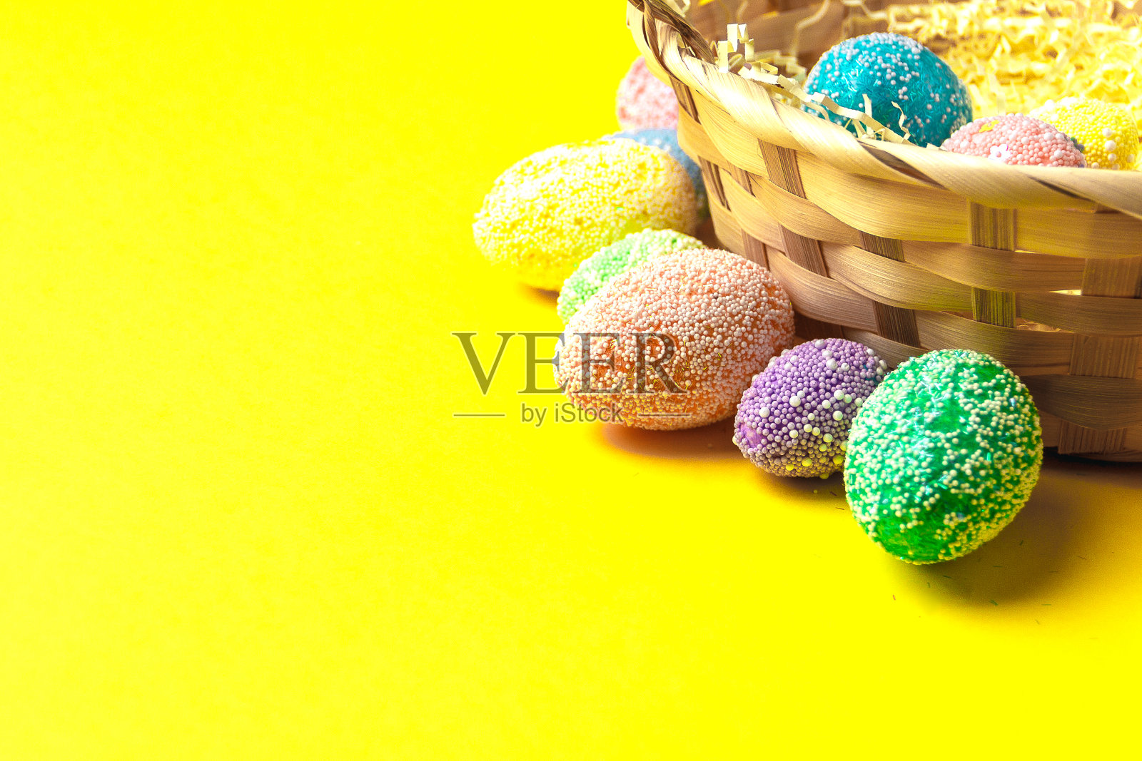 复活节快乐。用彩色粉笔在篮子里的鸡蛋在黄色的背景平铺文字空间。照片摄影图片