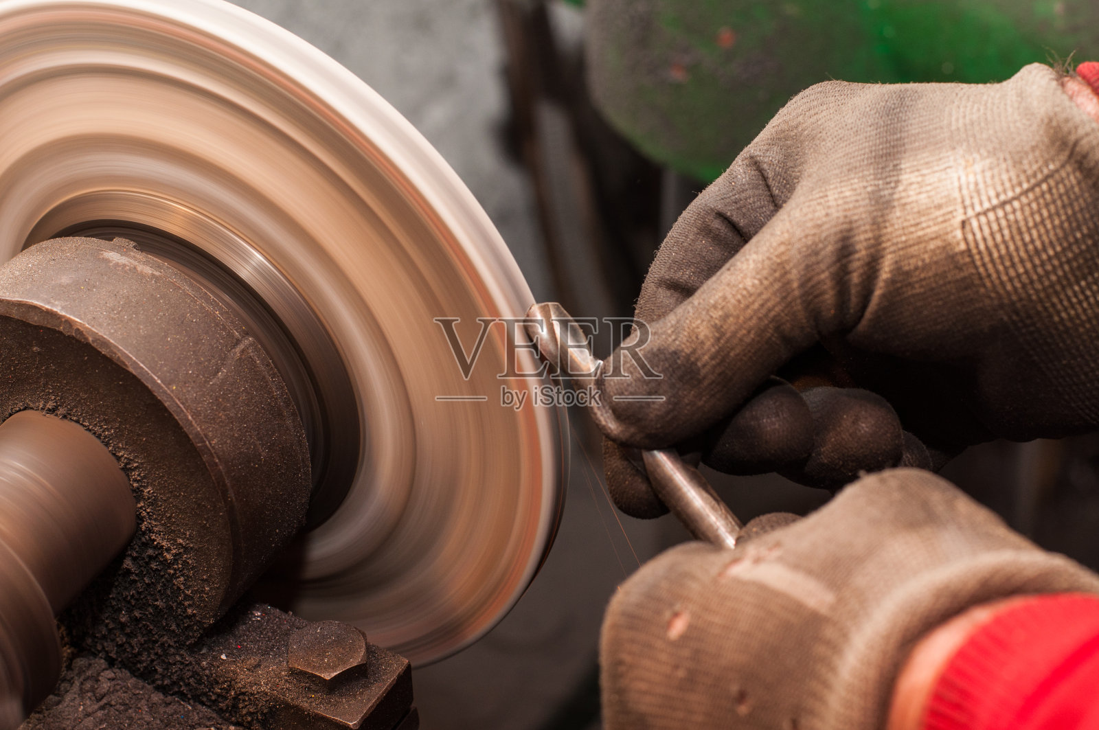 工人用磨石磨盘磨刀机磨钻。照片摄影图片