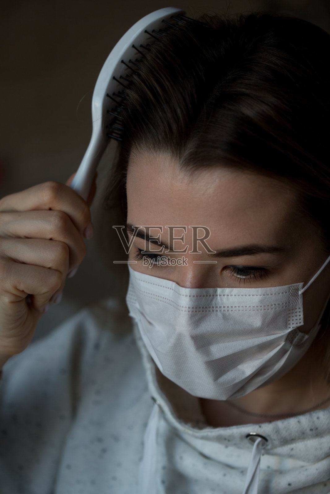 防冠状病毒的防护口罩。梳理头发。新型冠状病毒肺炎Covid-20。年轻女性看。照片摄影图片