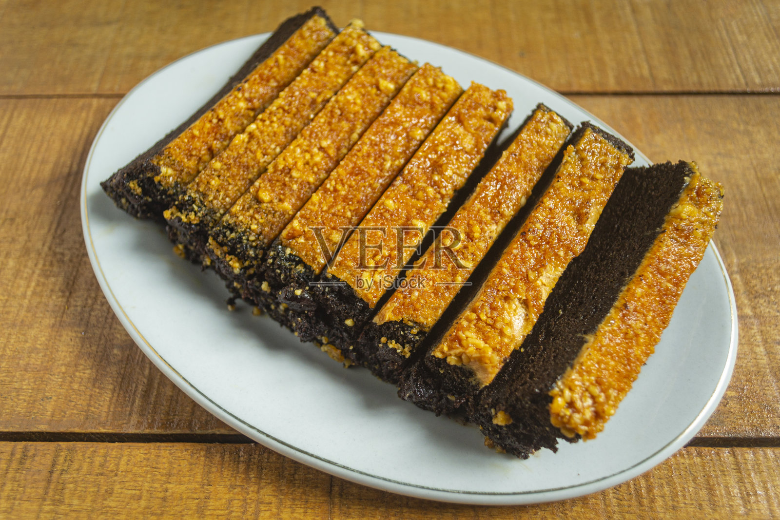 Kue bolu kacang或bolu蛋糕由面粉，巧克力，豆类和其他材料制成，有一种甜的味道。在木制背景上的白色盘子里照片摄影图片