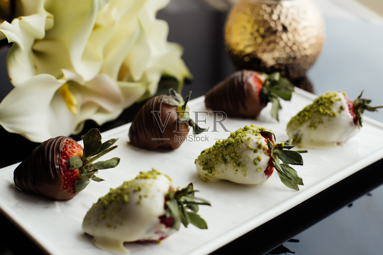 草莓甜点和一束黄色马蹄莲。照片摄影图片