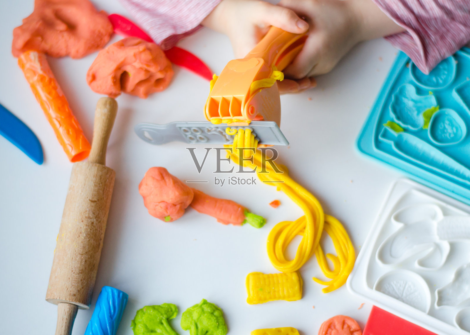 孩子的手用彩色粘土。孩子玩和创造蔬菜从玩面团。少女造型粘土。自制的粘土。照片摄影图片