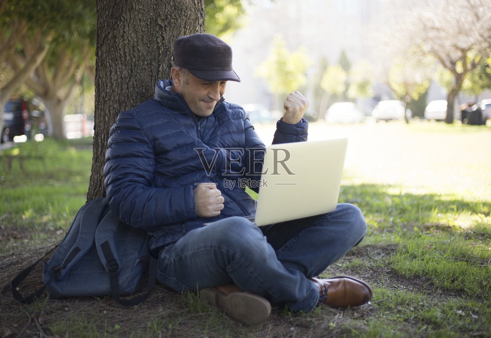 一个成熟的男人在城市公园用笔记本电脑展示他的成功照片摄影图片