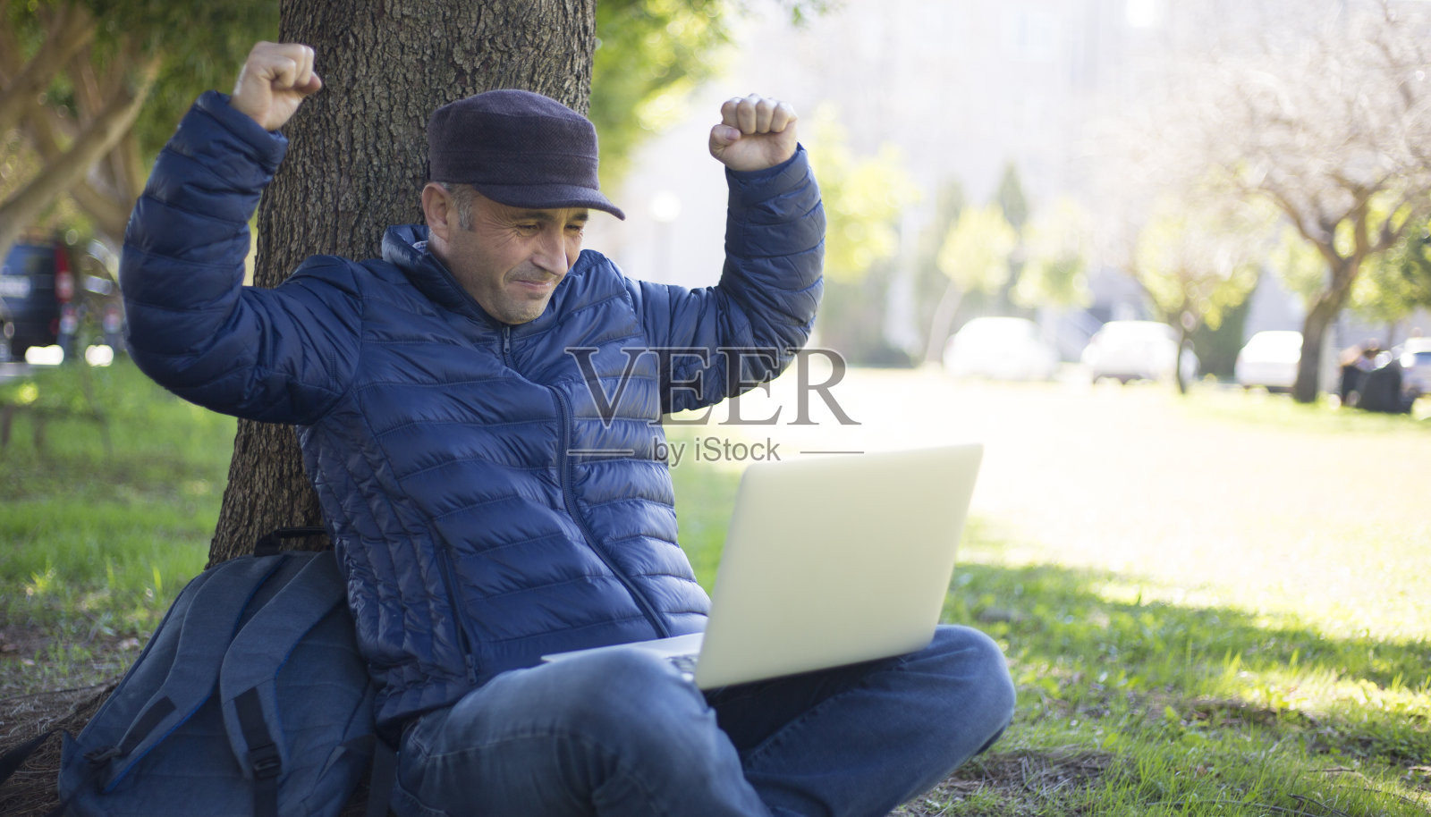 一个成熟的男人在城市公园用笔记本电脑展示他的成功照片摄影图片
