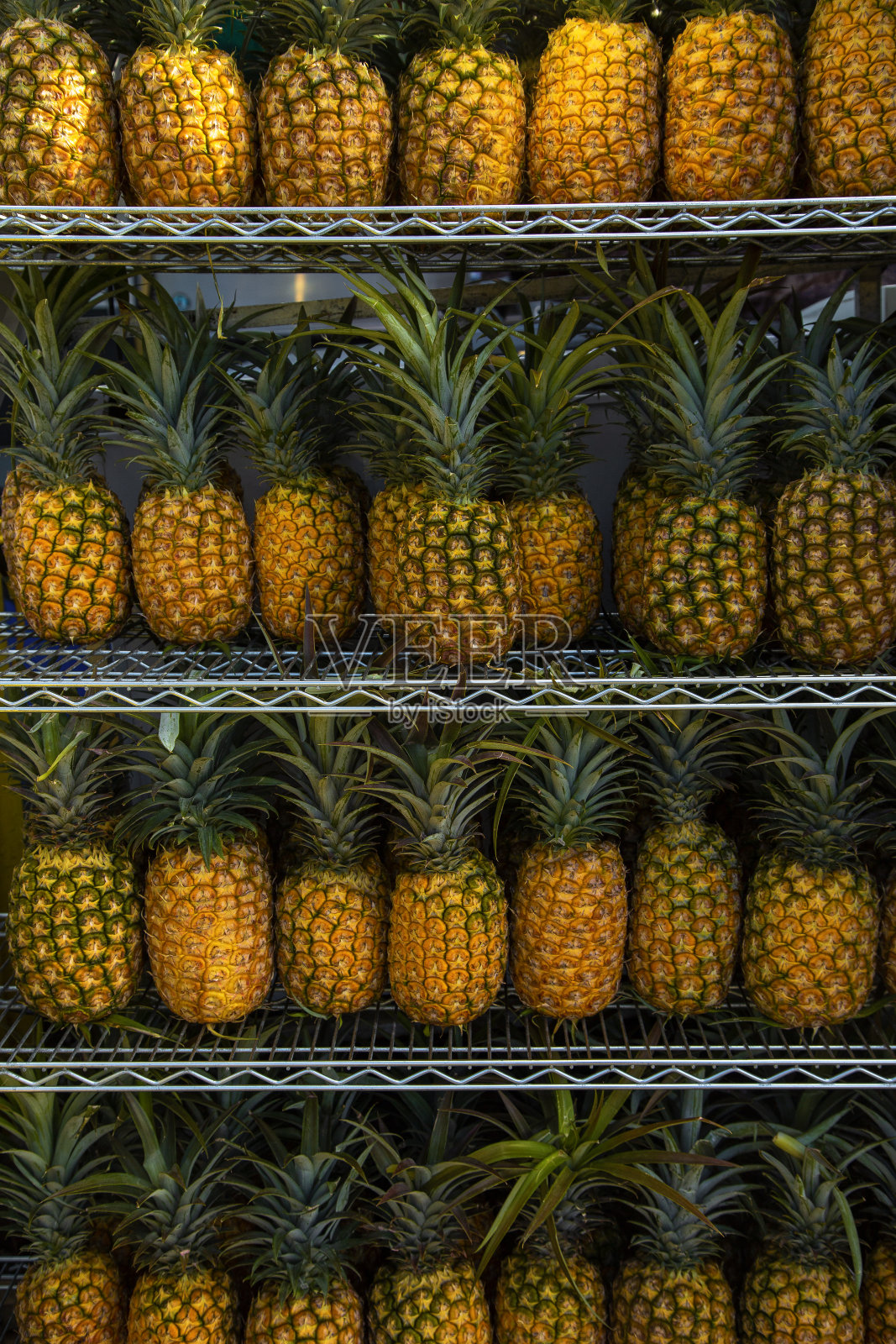 大型市场货架上满是新鲜成熟的菠萝。菠萝背景照片摄影图片