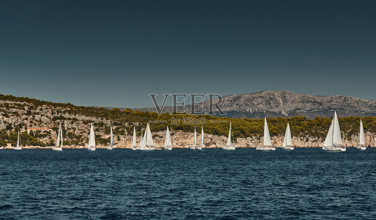 美丽的海景与帆船比赛，在地平线上的帆船比赛，一场激烈的比赛，明亮的色彩，岛上的风车是背景照片摄影图片