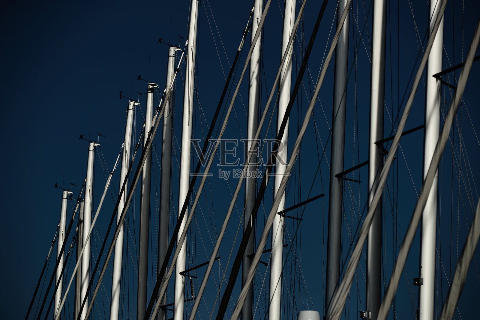 帆船的桅杆数以蓝天为背景，一场帆船赛，桅杆倒影在水面上，绳索和铝，色彩鲜艳照片摄影图片