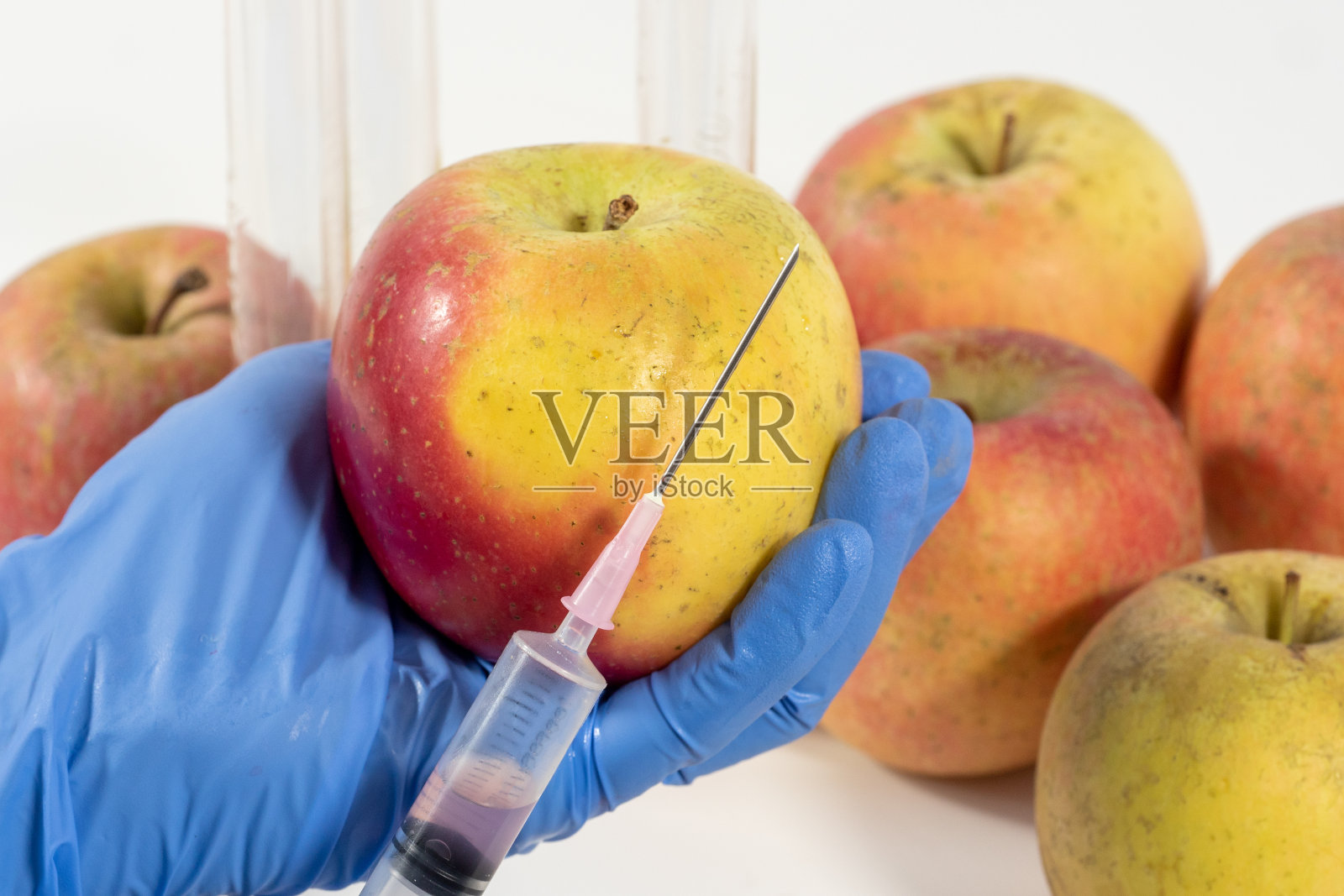 戴手套的妇女使用注射器。对水果和蔬菜进行基因改造。照片摄影图片