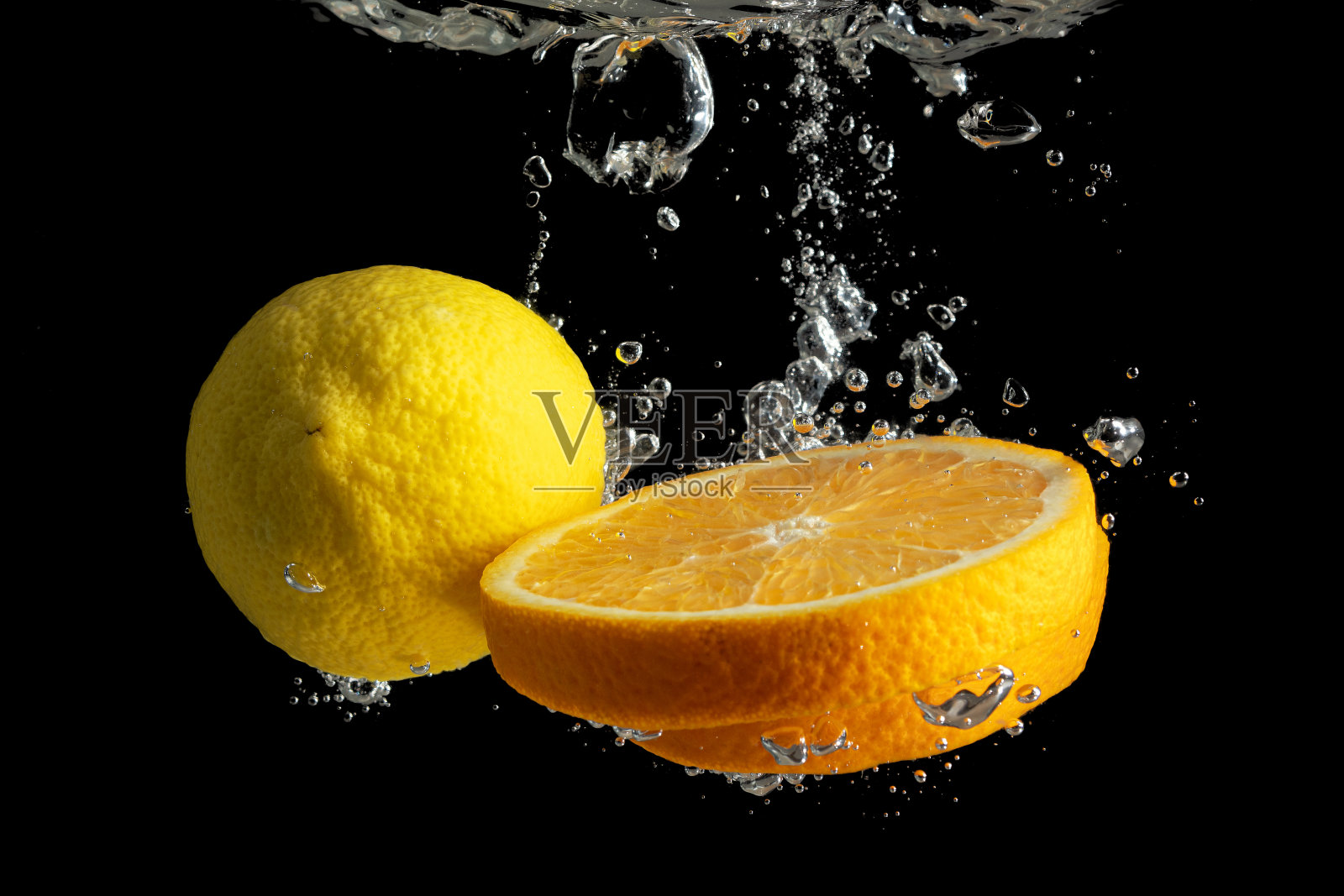 新鲜切片橙子和柠檬水飞溅孤立在黑色背景。最小的食品的概念。照片摄影图片