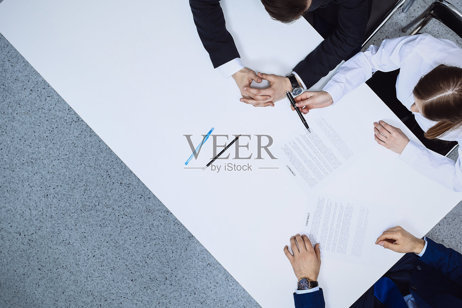 一群商人和律师坐在桌子旁讨论合同文件，从上面看。商人正在签署协议后的文件照片摄影图片