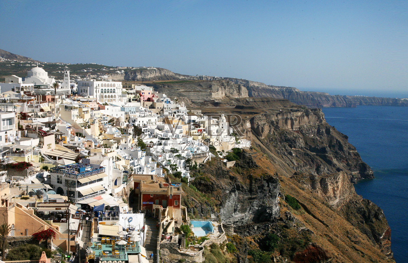 希腊圣托里尼岛上美丽的伊亚镇。位于爱琴海火山口的传统白色建筑和带有蓝色圆顶的希腊东正教教堂。照片摄影图片
