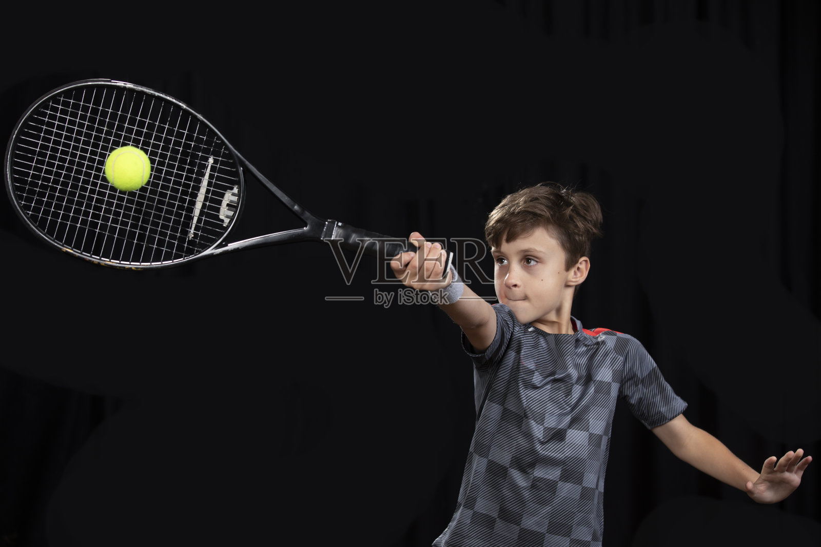 在黑色背景上打网球的男孩照片摄影图片