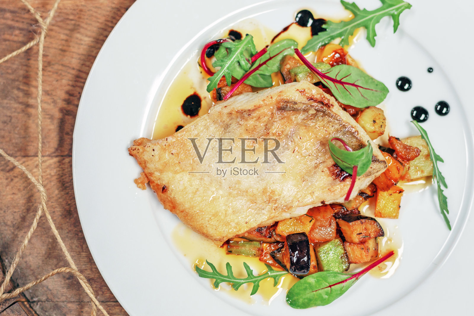 炒比目鱼配蔬菜，西葫芦，绿色在木背景。鱼、海鲜和蔬菜。照片摄影图片