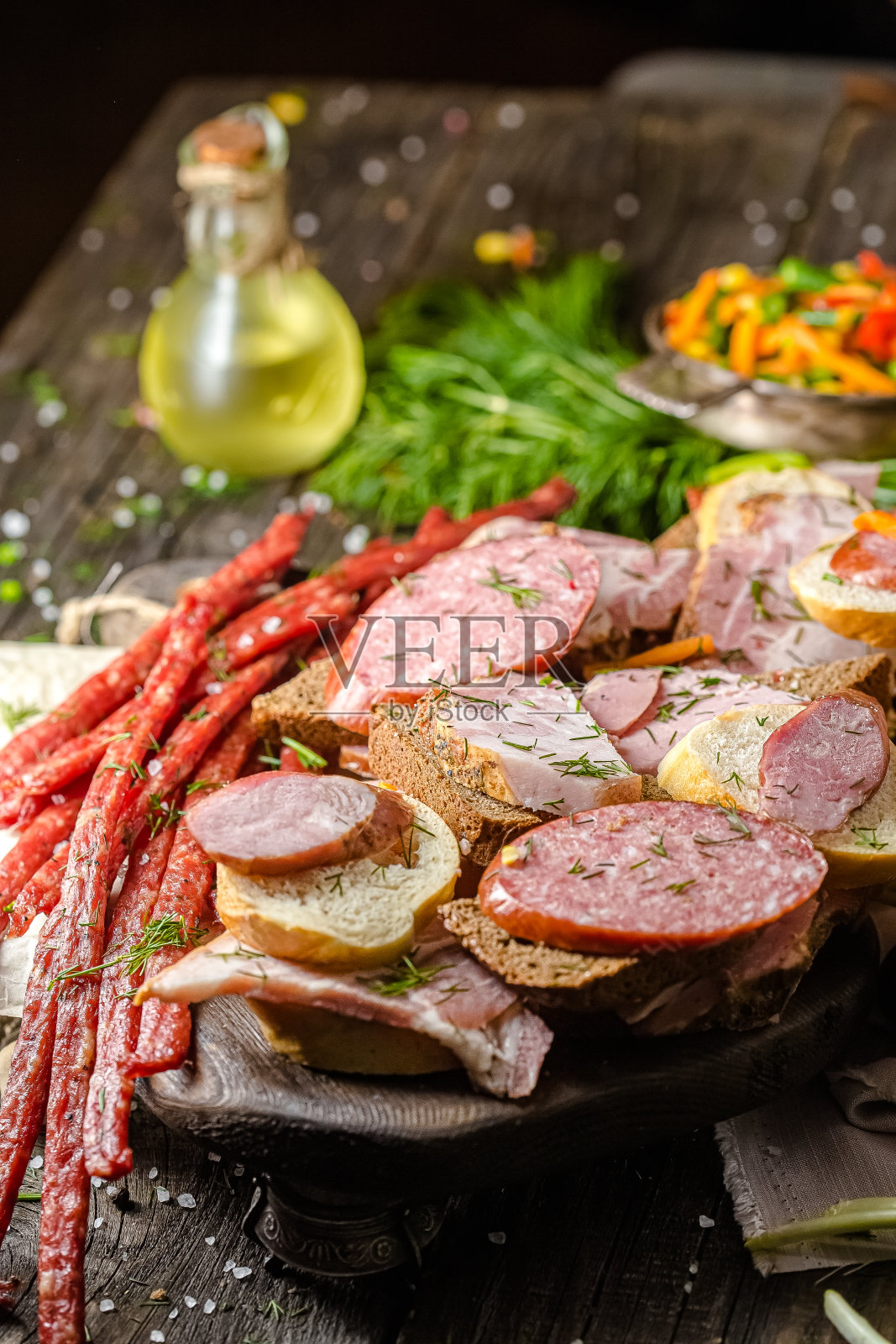 三明治与不同的切片香肠，熏肉，黑和白面包，肉类零食啤酒，新鲜的香草，乡村桌子或背景照片摄影图片