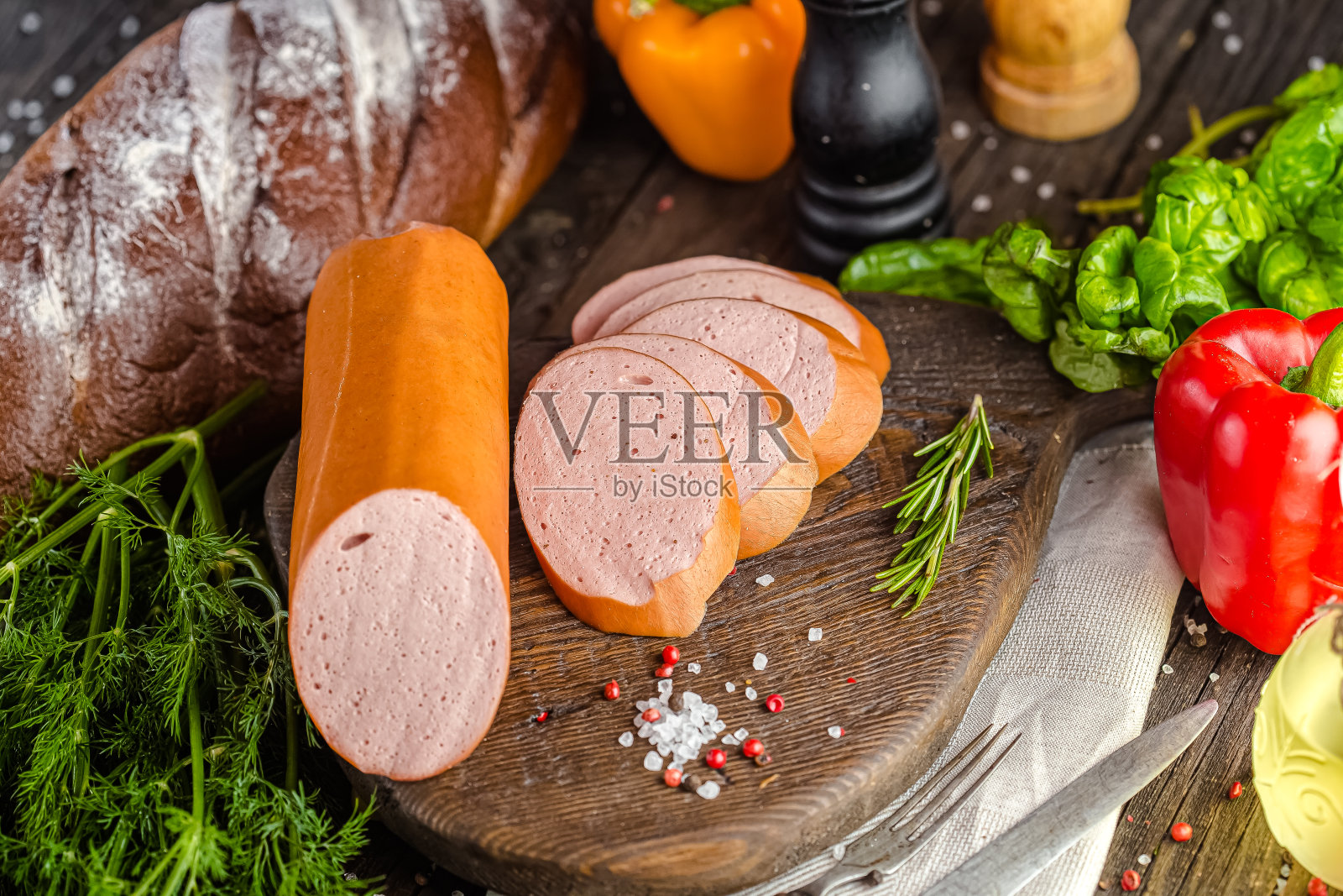 乡村的木制背景，一个大的自制香肠躺在砧板上，切成块，顶部和侧面拍摄，黑面包和蔬菜照片摄影图片