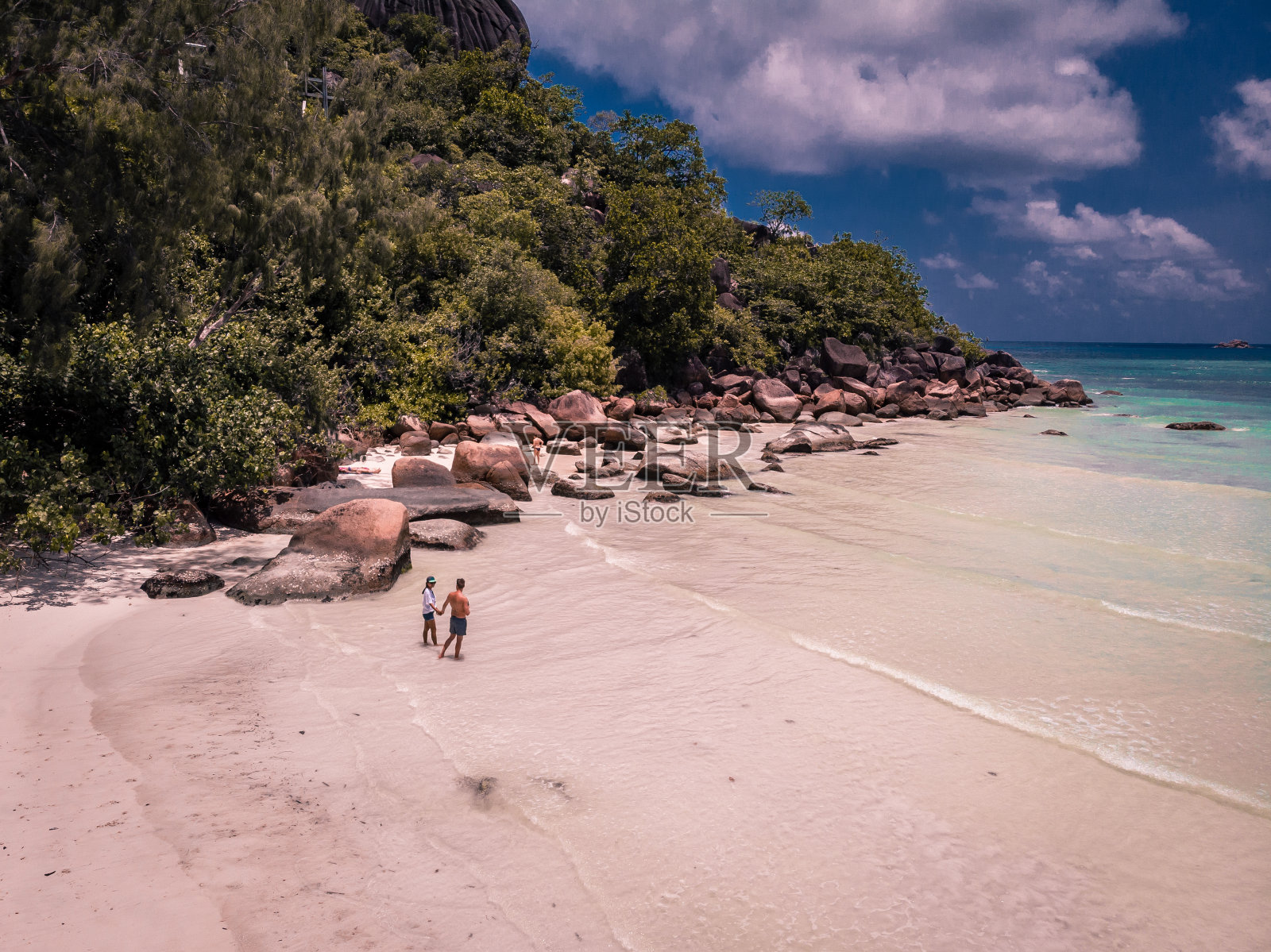 塞舌尔热带岛屿，Praslins岛，一对夫妇在热带海滩上散步，棕榈树照片摄影图片