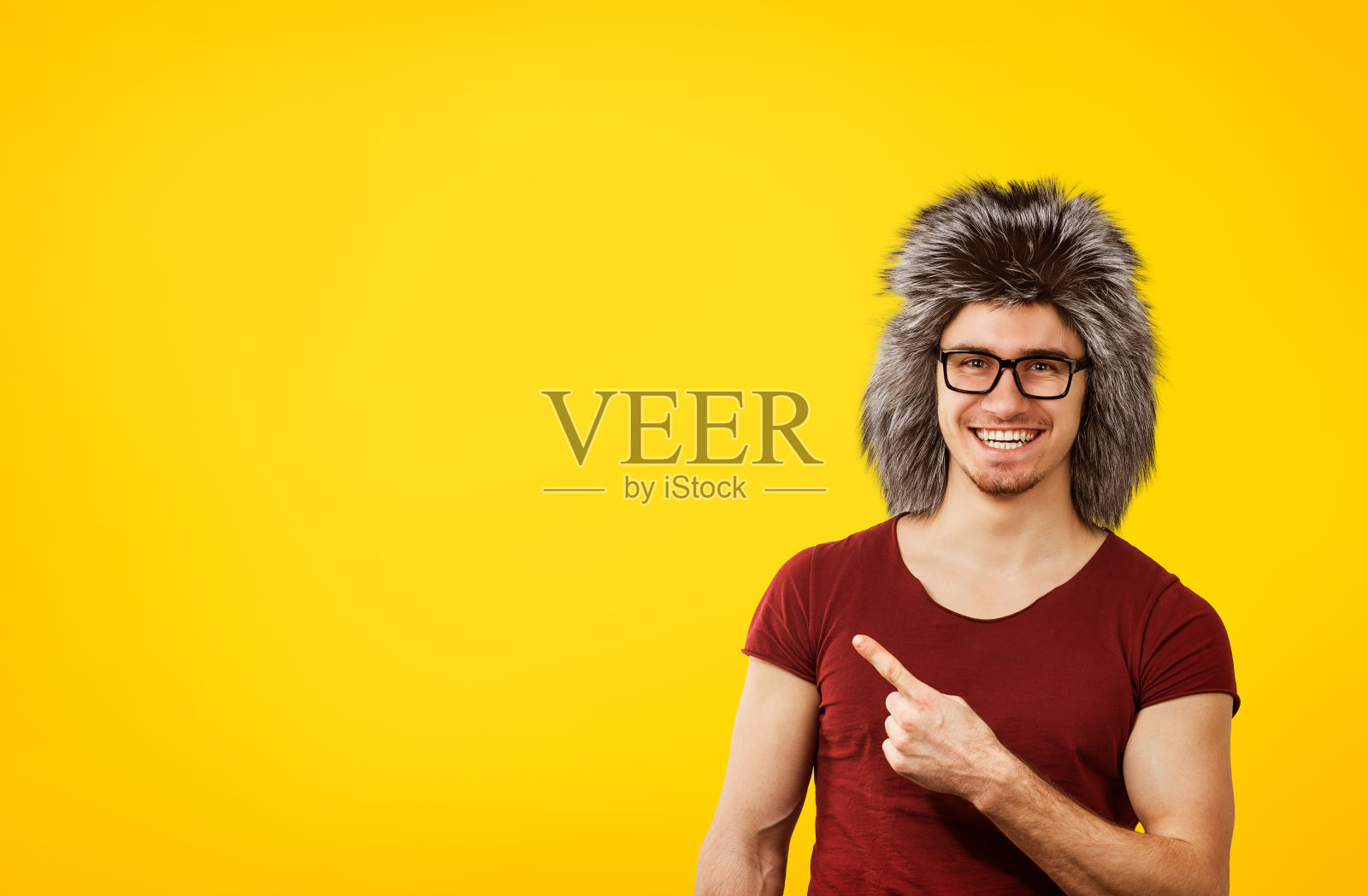 年轻的潮人戴着眼镜和冬天的帽子指着幸福的方向照片摄影图片