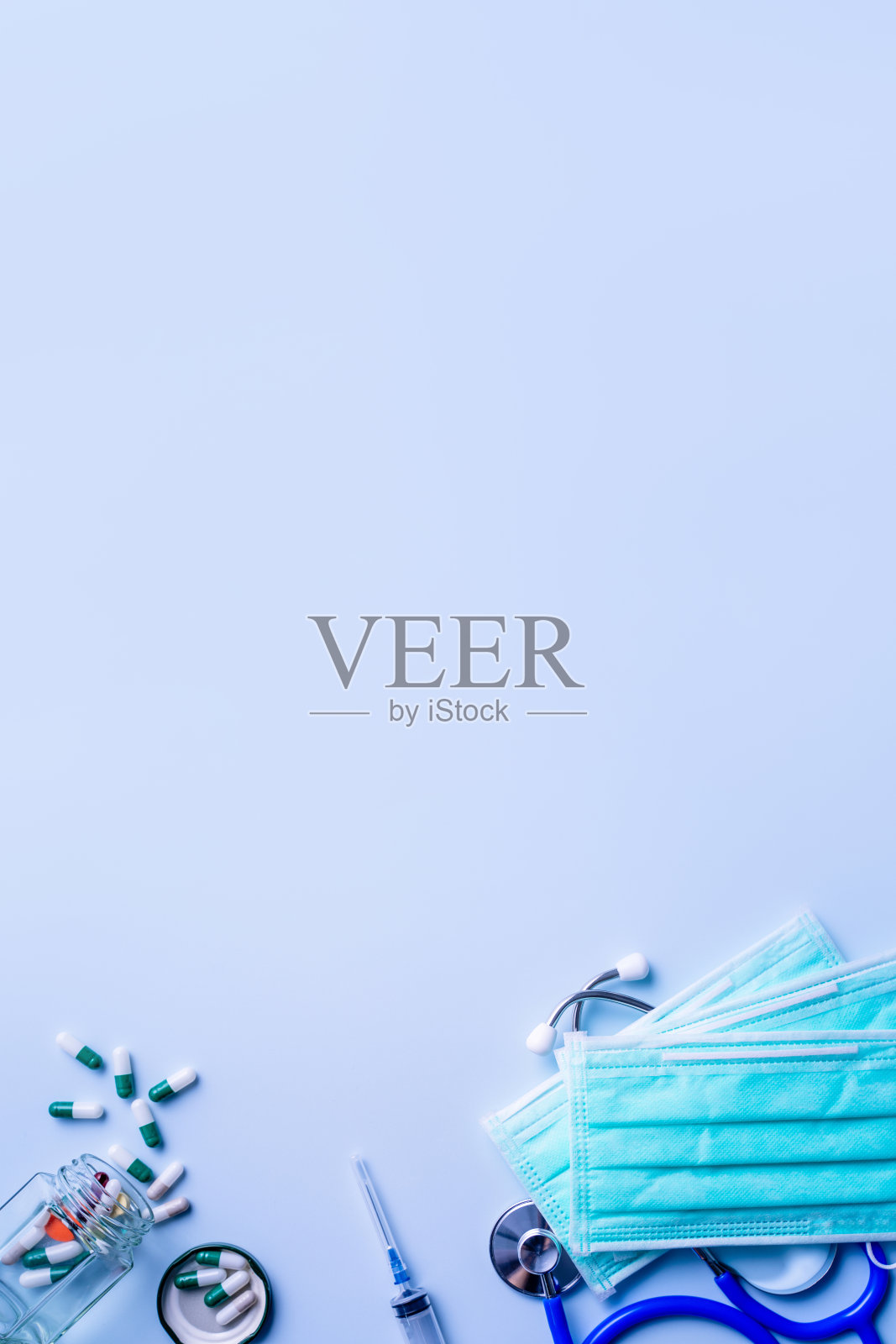 口罩与药片，听诊器，注射器医疗用品对象隔离在蓝色背景，俯视图，平躺，头顶拍摄，病毒防护概念。照片摄影图片