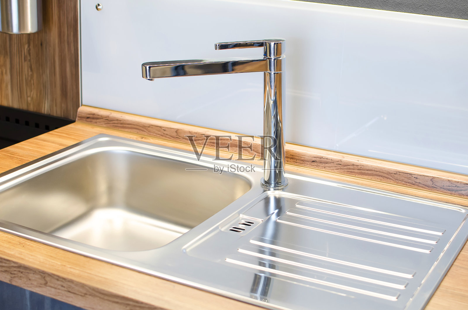 新的水龙头和不锈钢水槽。现代舒适的厨房。照片摄影图片