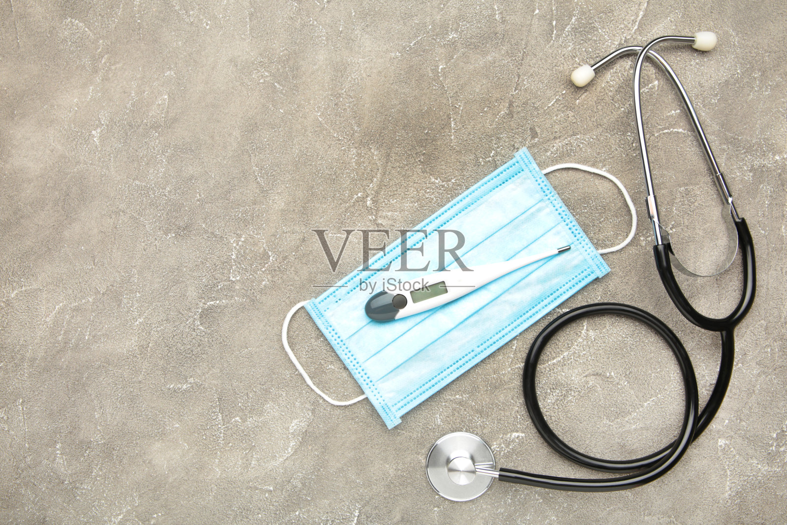 温度计、听诊器和防护面罩置于灰色混凝土背景上。健康的概念。副本的空间。照片摄影图片