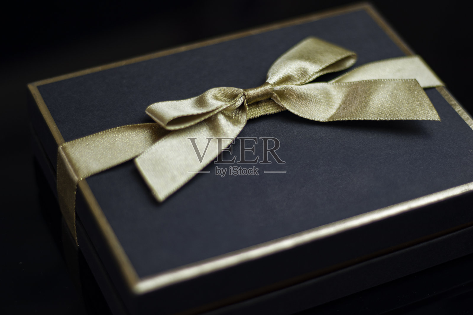 特写深蓝色礼盒和金色丝带在黑色的背景照片摄影图片