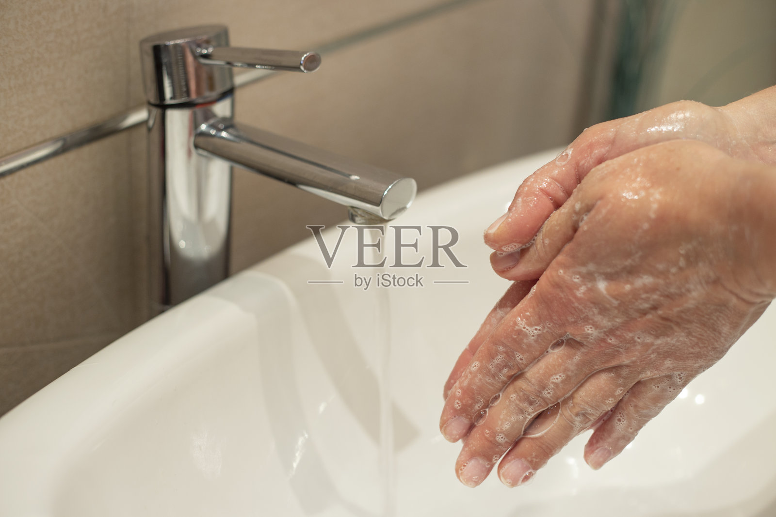 一位妇女在水龙头下用流动的水深深地洗手。洗手对于避免冠状病毒和细菌感染非常重要照片摄影图片