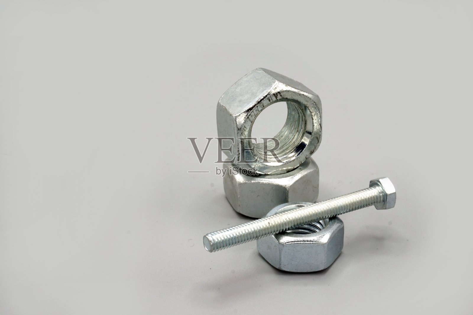 灰色背景上隔离的金属螺钉和螺母。新的和闪亮的铬螺丝和螺母。副本的空间。照片摄影图片