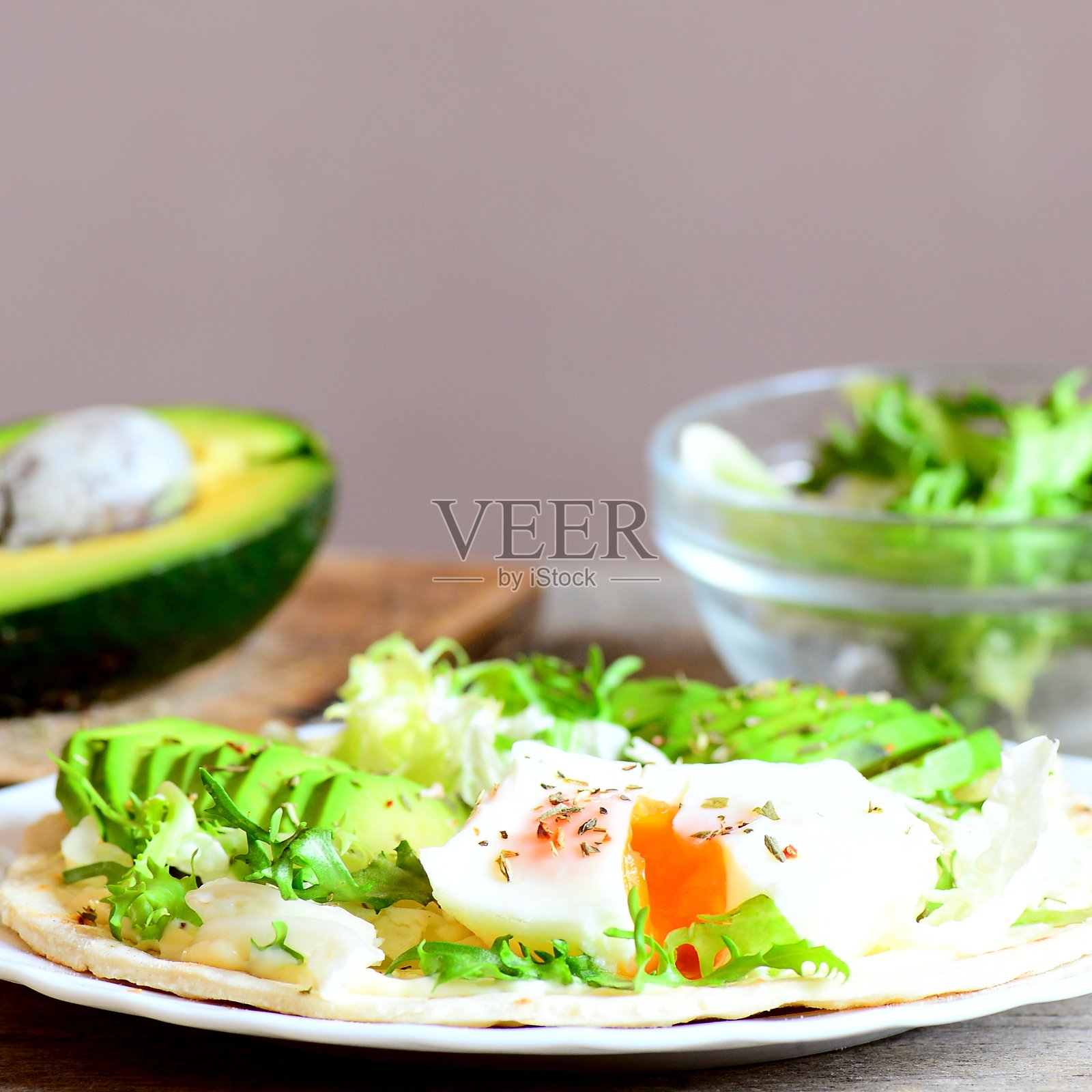 水煮蛋，牛油果片，沙拉，酱汁，香料在面粉玉米饼。牛油果半份，混合沙拉放在桌上的玻璃碗里。健康和快速的早餐主意照片摄影图片