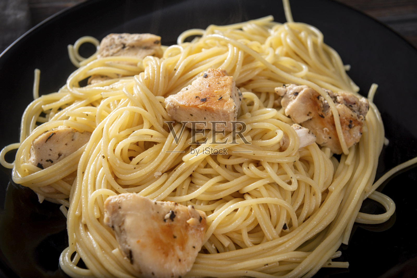 意大利面配鸡柳，黑色盘子，意大利面照片摄影图片