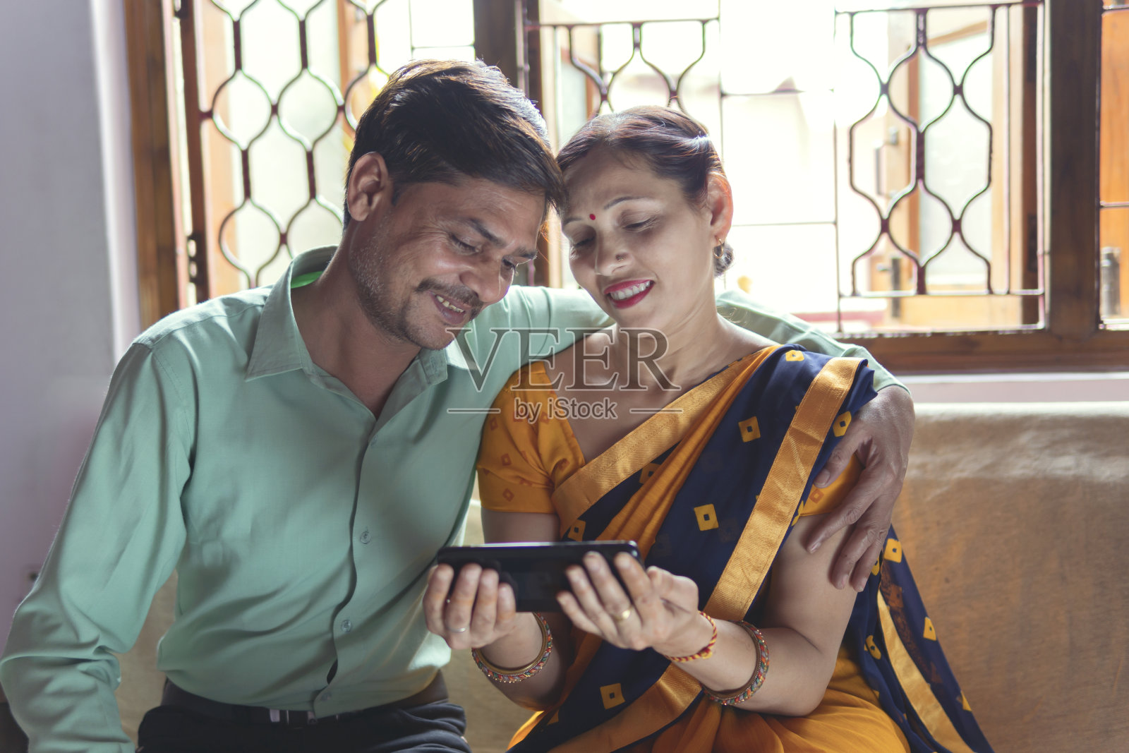 快乐的男人和女人一起放松，在家里使用手机。照片摄影图片