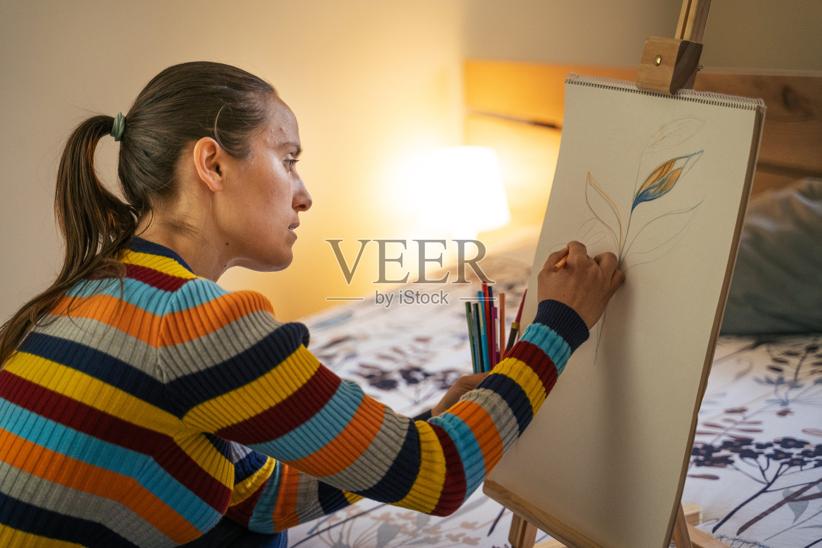 年轻女子在卧室里画画。艺术家在家工作。2019冠状病毒病大流行期间不要外出。照片摄影图片