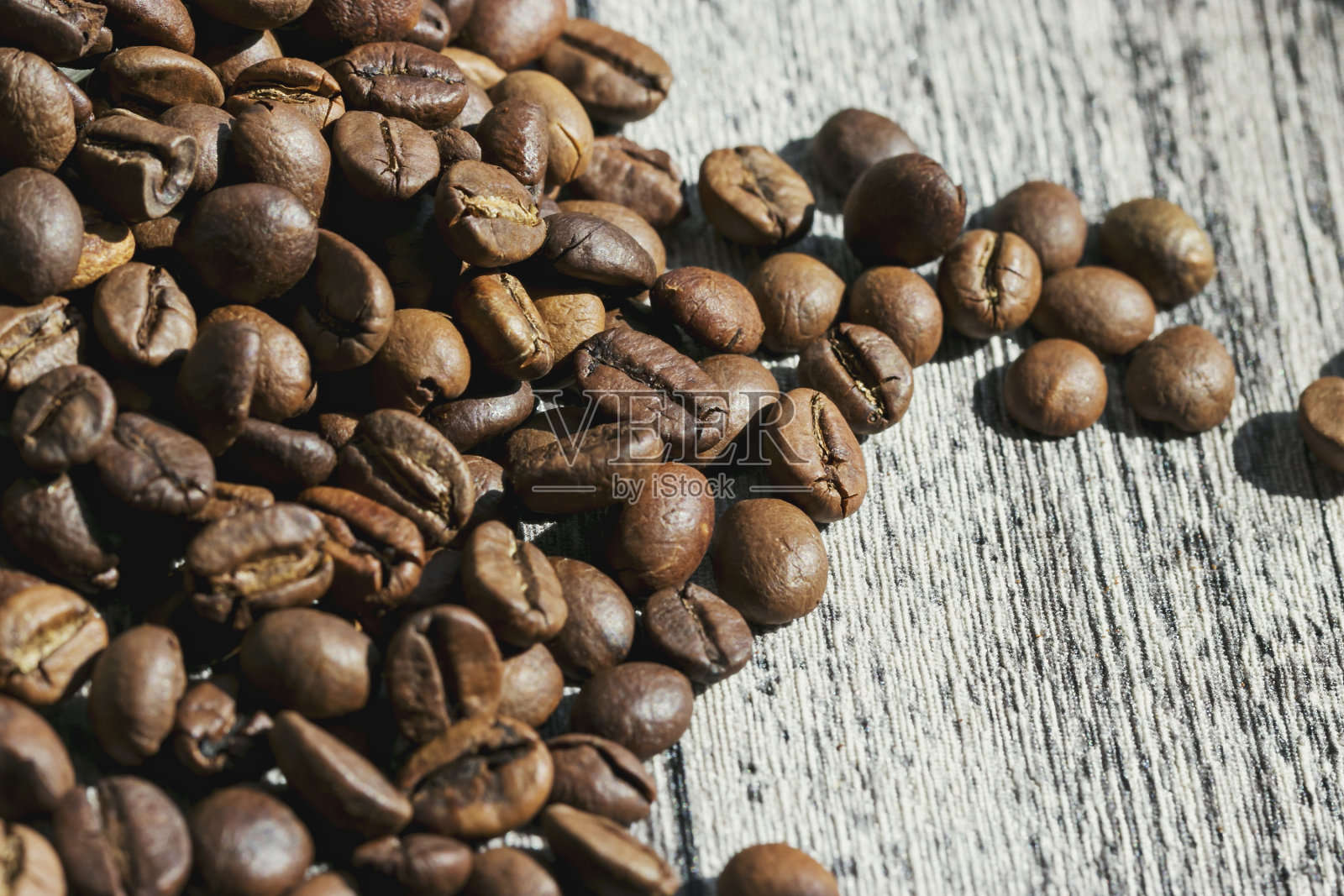 烘好的咖啡豆撒在桌子上。照片摄影图片