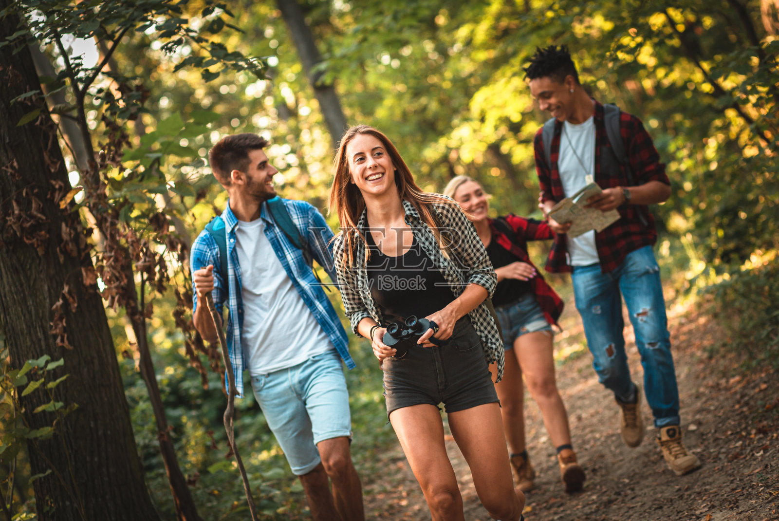 一组四个朋友一起徒步穿越森林。照片摄影图片