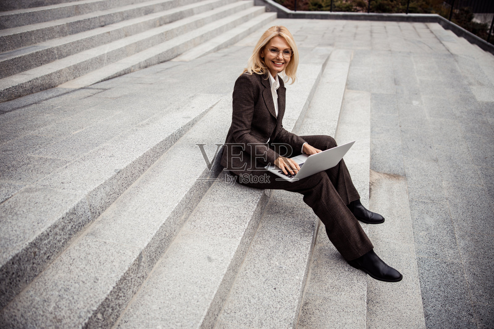 带着笔记本坐在户外的漂亮女人照片摄影图片